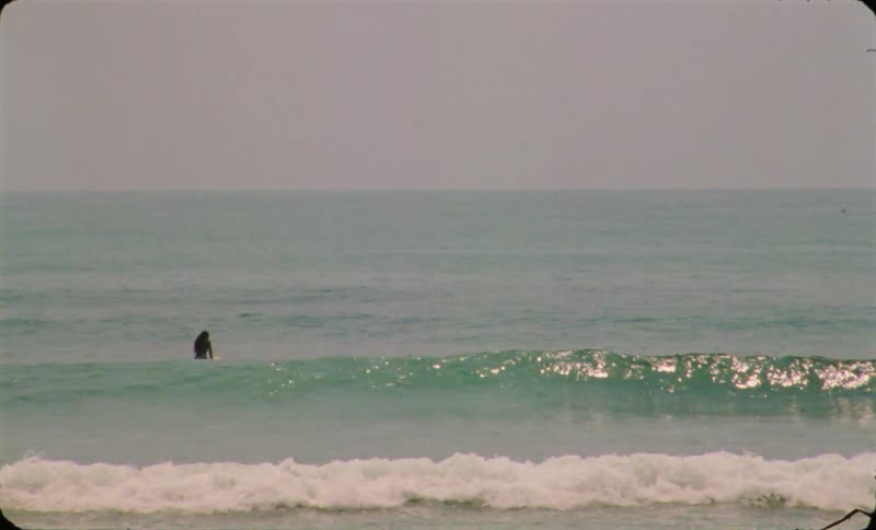 A person is surfing on ocean water during dusk