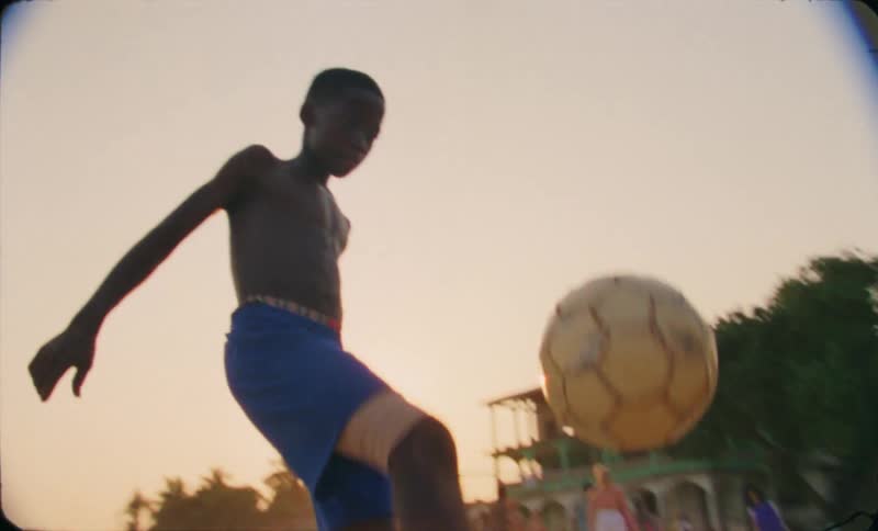 Teenage boy juggling soccer ball on the beach during the day