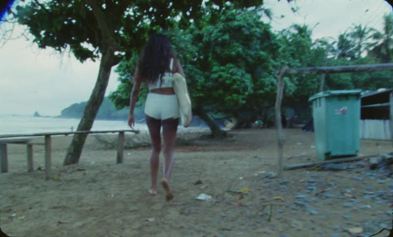 A woman carries a surfboard to the beach