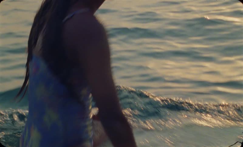 A young woman is sitting down on her surf board
