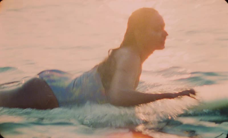 A female is swimming on a surf board in the ocean