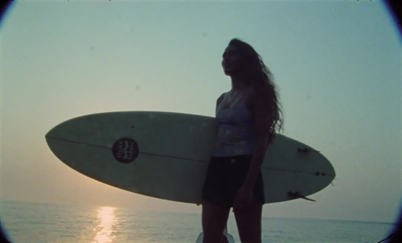A woman is holding a surfboard near the ocean water
