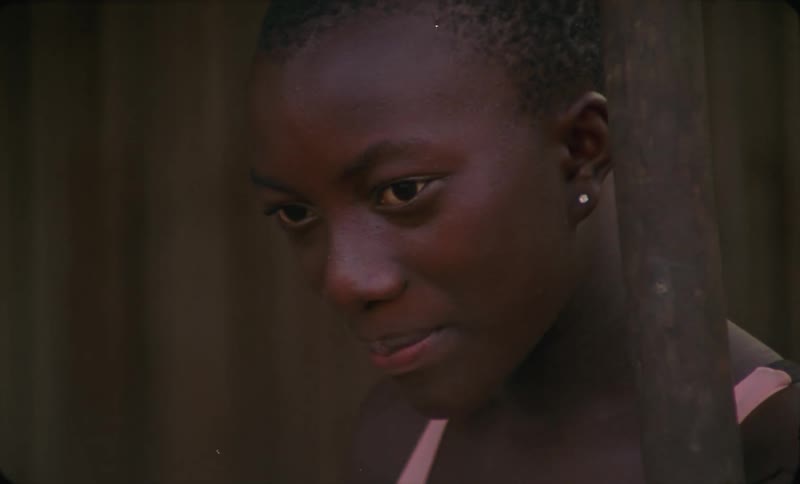 A female child is standing outdoors near a fence