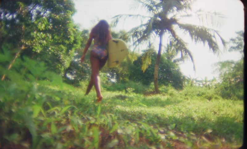 The view is of a young woman holding her surfboard