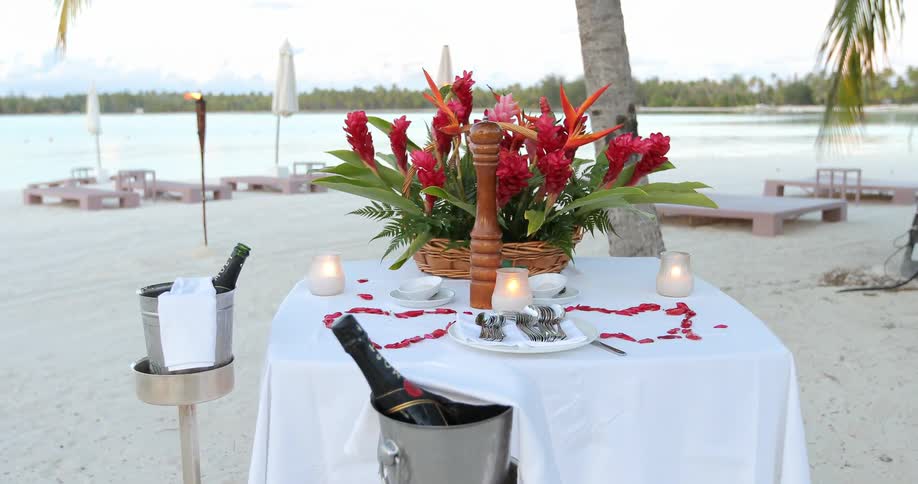 A dinner table set for a couple on the beach