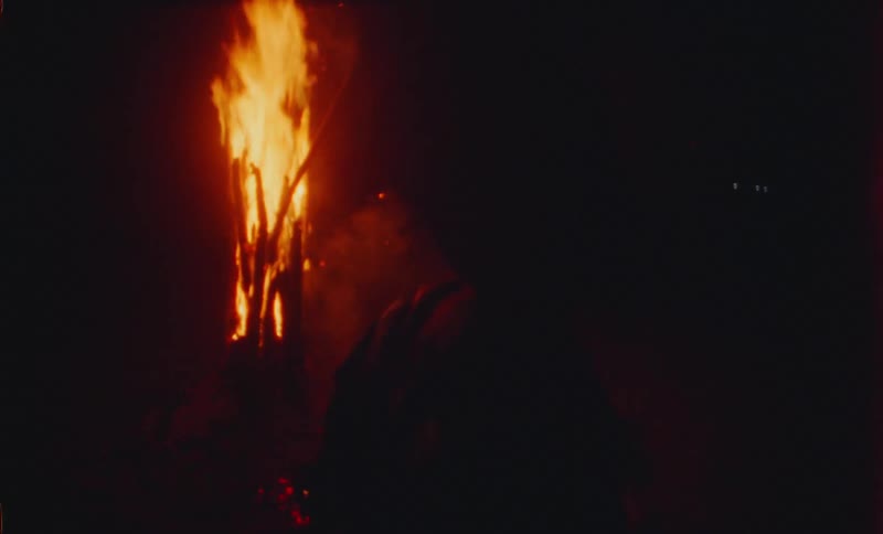 A male is dancing around a bonfire at night
