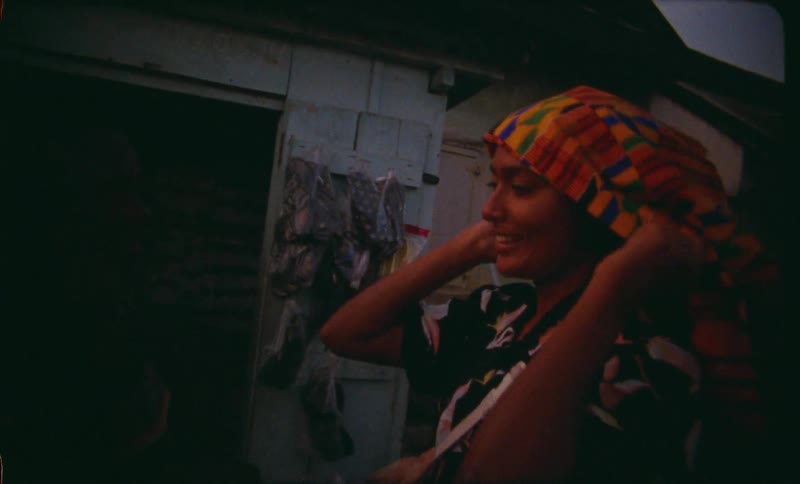 A woman putting on a colorful scarf and interacting with a teenage boy