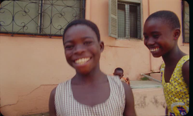 Two young girls laugh while dancing around outside