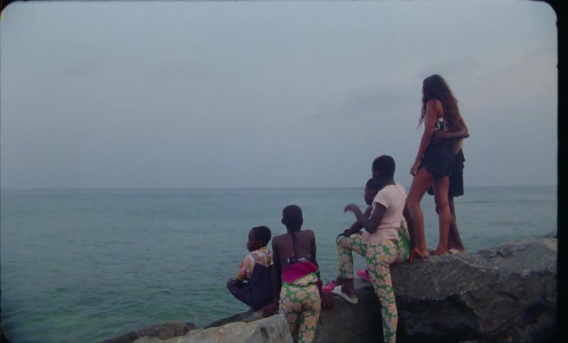 A group of women look out over the ocean while standing together on a rock formation on a cloudy day