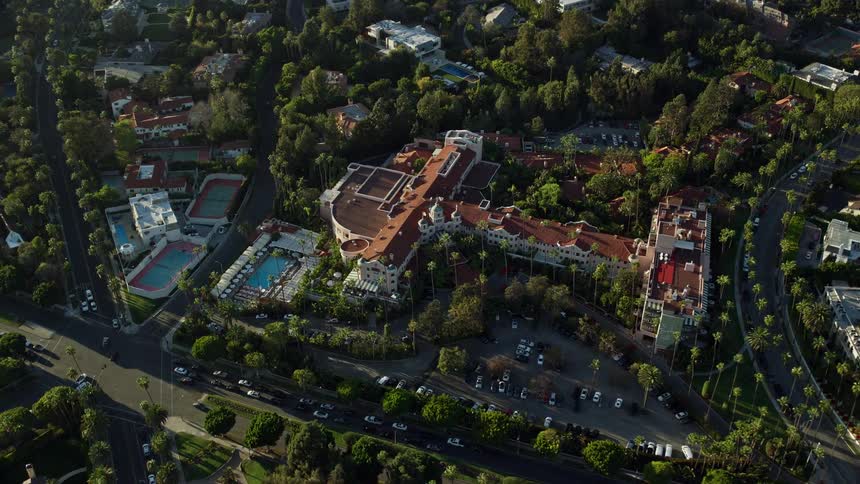 Approaching the luxurious Beverly Hills Hotel captured in stunning aerial footage complete with sunshine stunning and tilting down for an epic view of the Southern California heavens