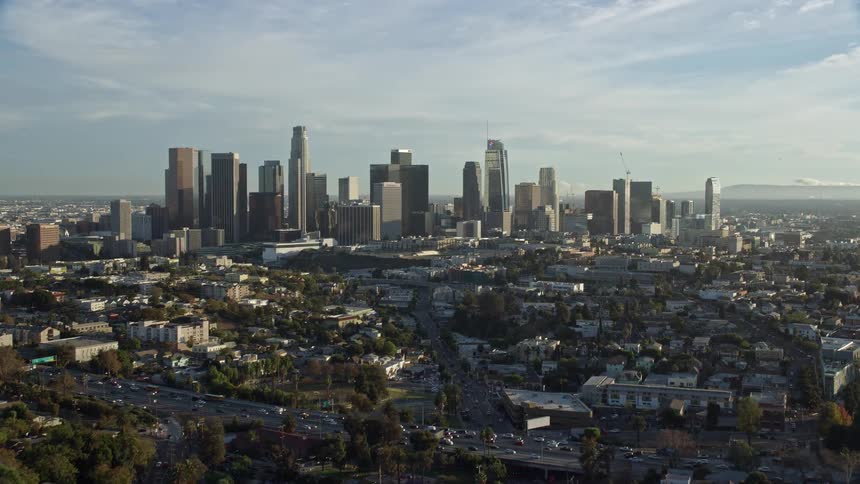 An epic aerial flyover of Downtown Los Angeles skyline captured during spring or summer while approaching from Echo Park Lake