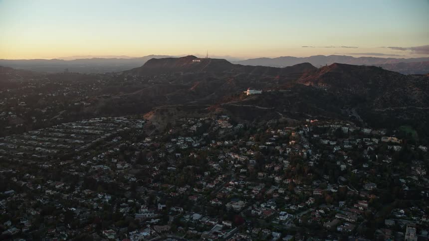 Aerial view of Hollywood Sign and Griffith Observatory during twilight approached from Los Feliz neighborhood in Los Angeles CA