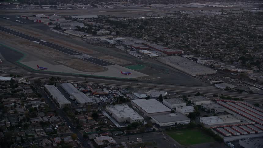 Aerial footage showing commercial airplanes at the end of a runway in Burbank Airport during twilight