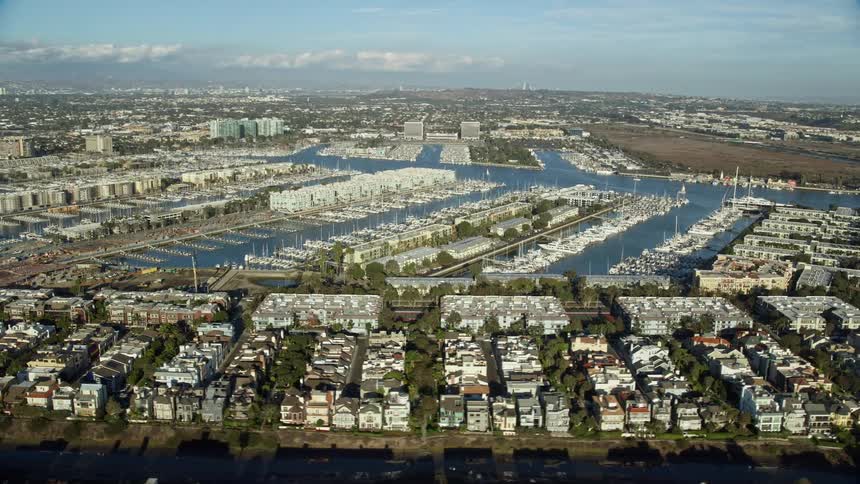 A breathtaking aerial view of waterfront apartments overseeing marinas filled with yachts in the harbor of Marina Del Rey California during a sunny day