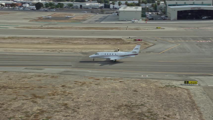 Private jet taxiing down runway at Long Beach Airport California during partly cloudy skies