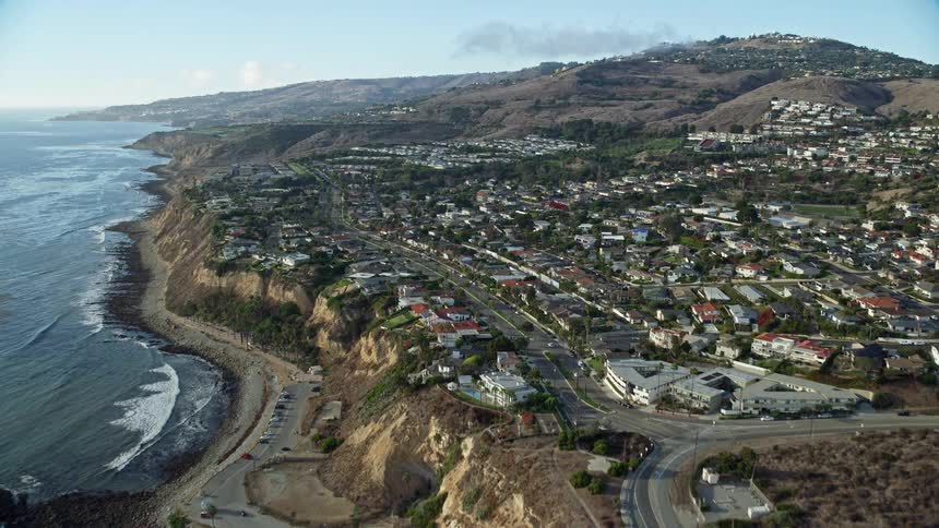 An epic aerial shot tilting up from kelp in the ocean to reveal a coastal neighborhood in San Pedro California with stunning views of the surrounding cliffs and park