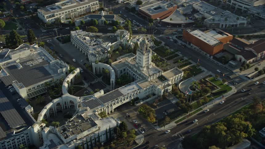 A beautiful aerial shot flying by and away from Beverly Hills City Hall a stunning government building situated in the heart of Beverly Hills California