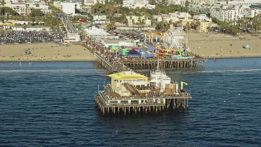 Tourists enjoy the sunny day at Santa Monica Pier on a busy beach in Southern California in this aerial stock footage