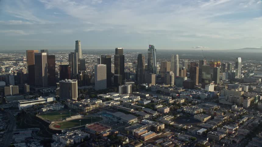 Approaching the iconic high rises of downtown Los Angeles on a partly cloudy day showcased in stunning aerial footage
