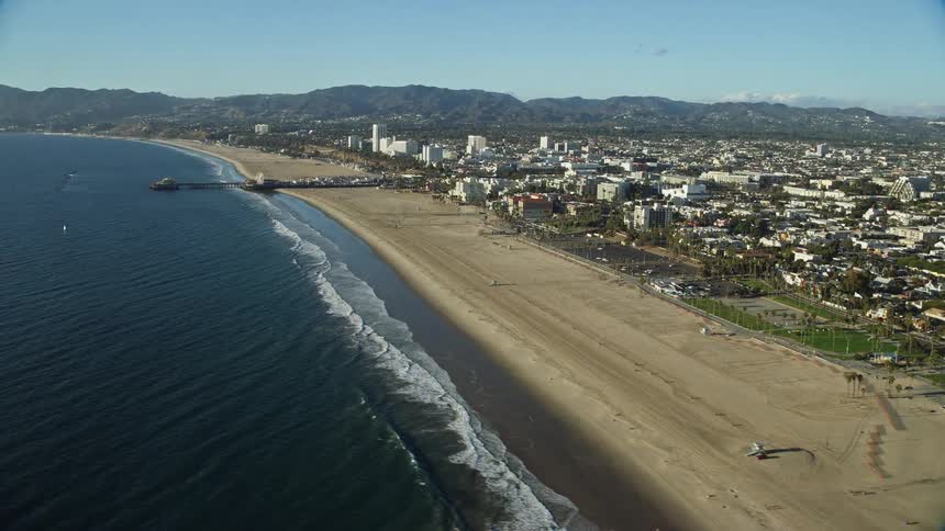 Approaching the historic Santa Monica Pier from above this aerial footage captures the bustling shoreline and residential areas of Southern Californias iconic beach town