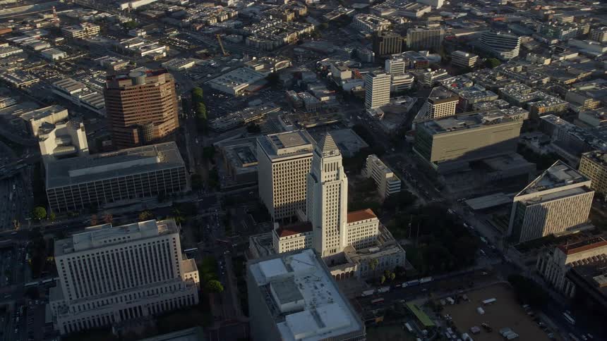 Aerial footage of Los Angeles City Hall in downtown LA soaring above the city during a partly cloudy day in Southern California