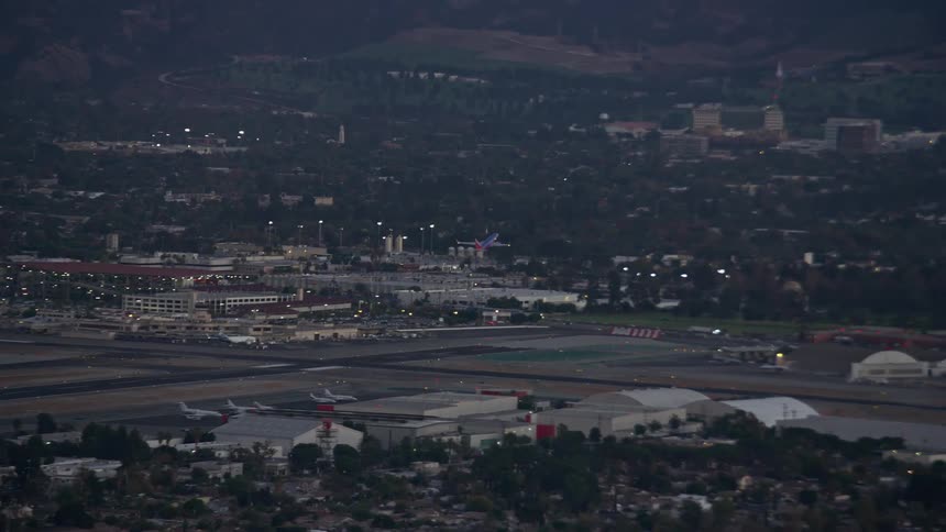 A commercial airplane takes off at twilight from Burbank Airport California