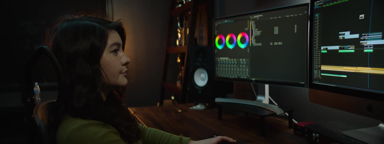 Woman sits in office in front of a pair of monitors