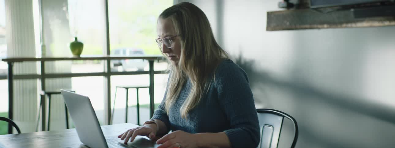 A woman is sitting at a table working on a laptop computer