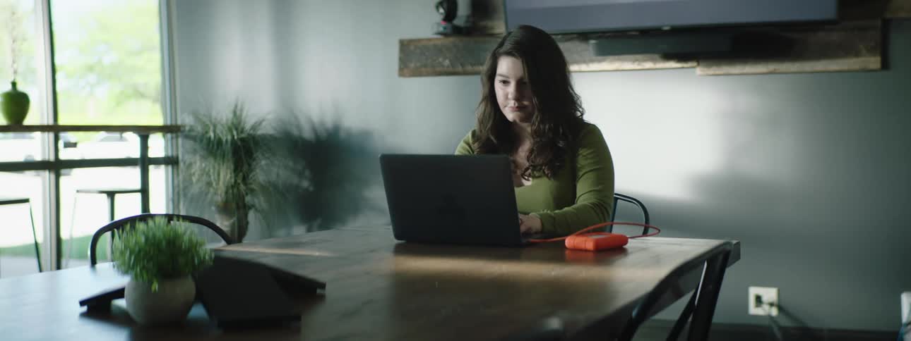 Woman sits at dining table using laptop