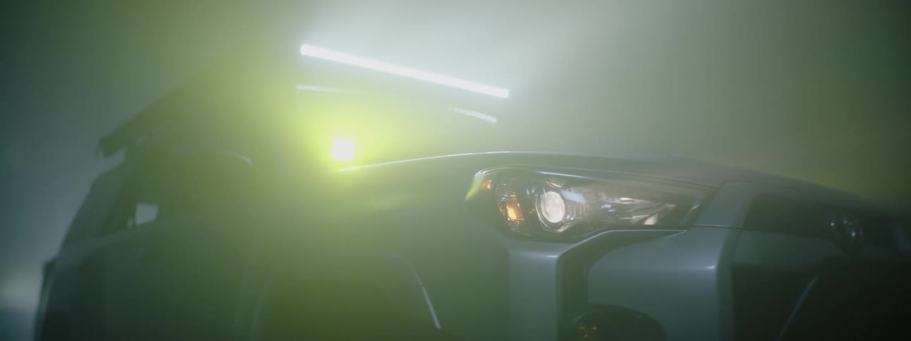 A front fender of an suv with headlights a light bar and yellow accents lights on at night