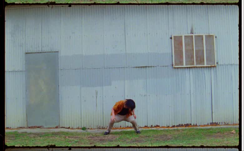 A woman dances hip hop style outside a building