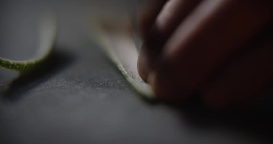 Close up of lime peel being sliced on a slate surface