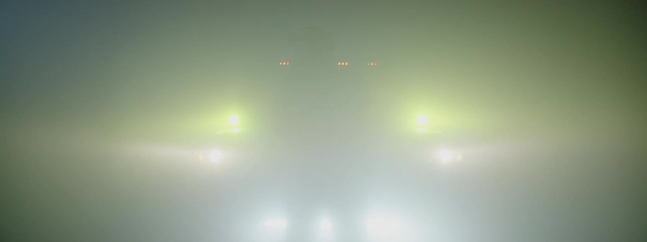 Man standing in front of suvtruck at nighttime while each set of lights turns on with succession and then off again