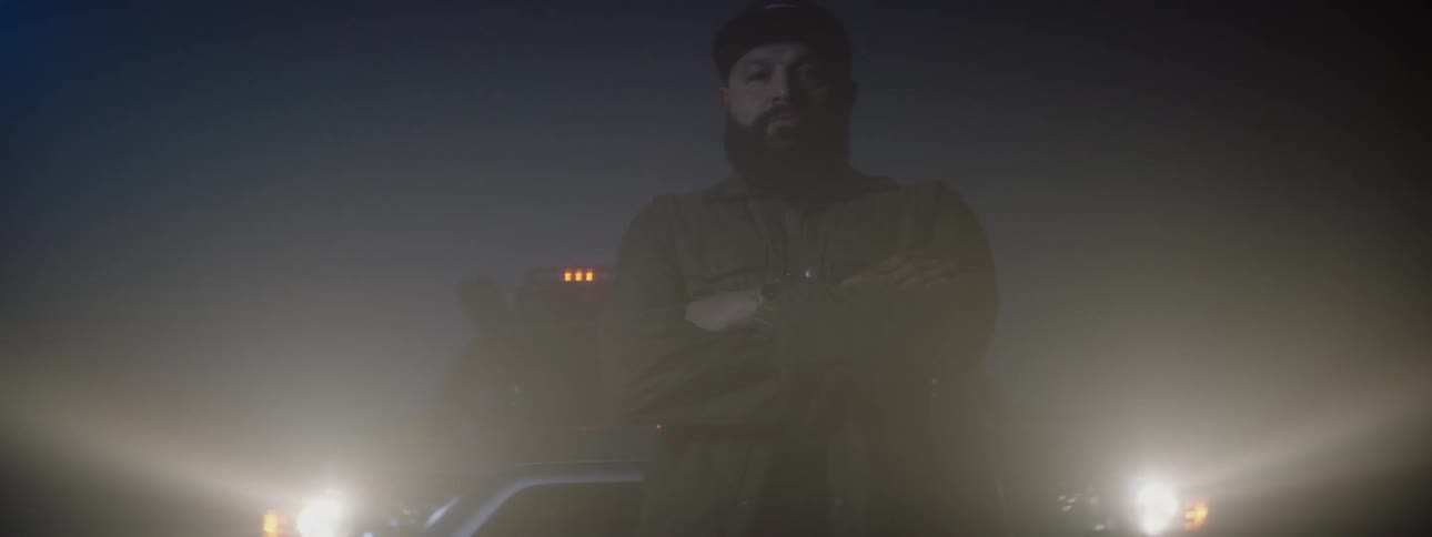 A man is standing in the fog by his truck