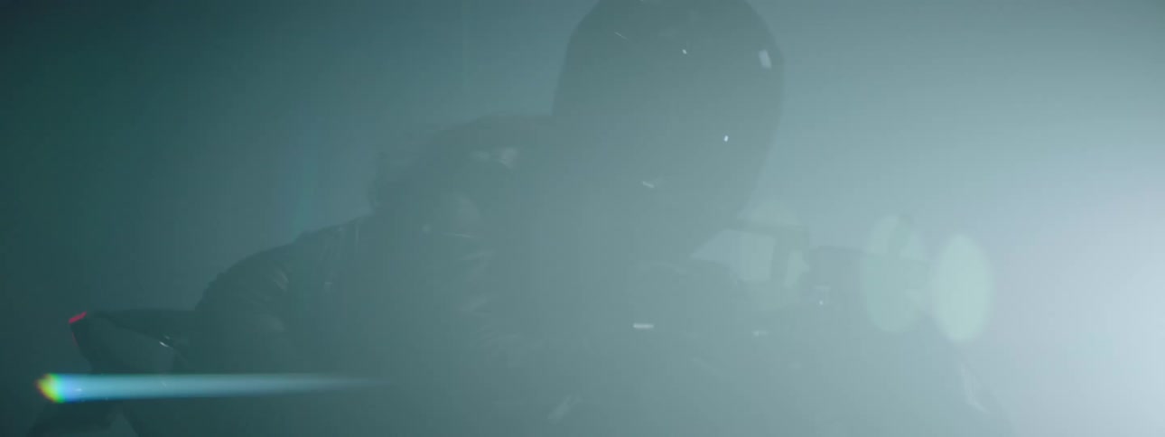 A woman riding a motorcycle wearing a black helmet at night as light flashes in front of her