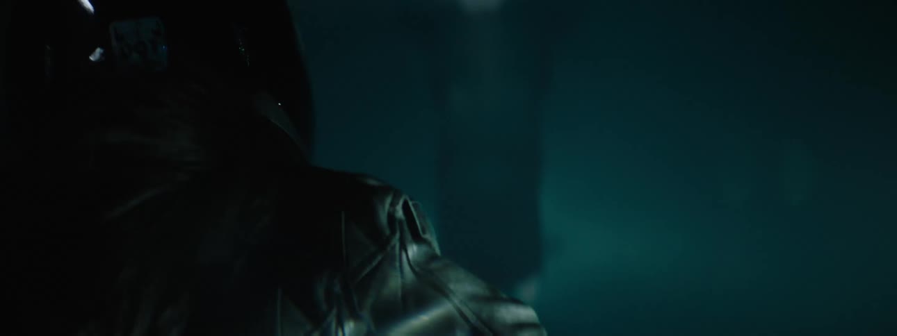 A woman wearing a back leather jacket and a black helmet is walking as a strobe light flashes