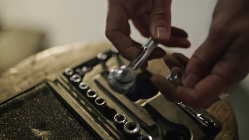 A mechanic is standing over a tool box putting a socket on a ratchet