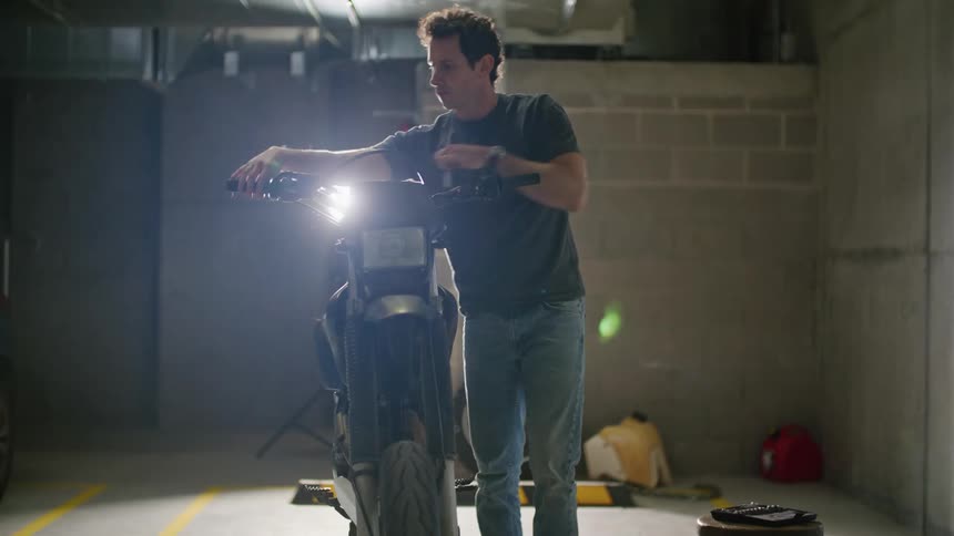 A young man is using a socket wrench to tighten the handlebar on his motorcycle