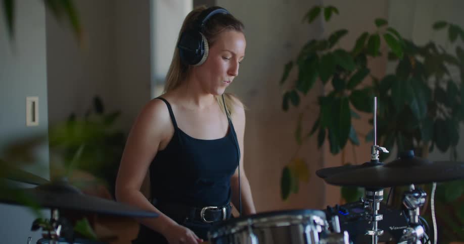 Woman wears headphone while playing drums