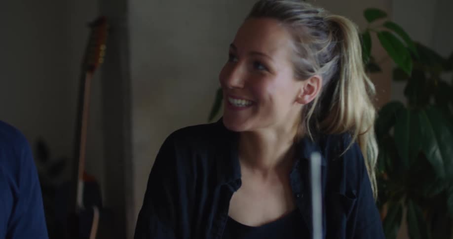 A woman and a man talking smiling and laughing near an indoor plant and instruments