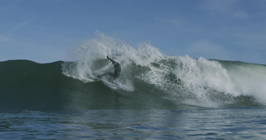 A man in a wet suit skillfully surfs the barrel of a wave without wiping out