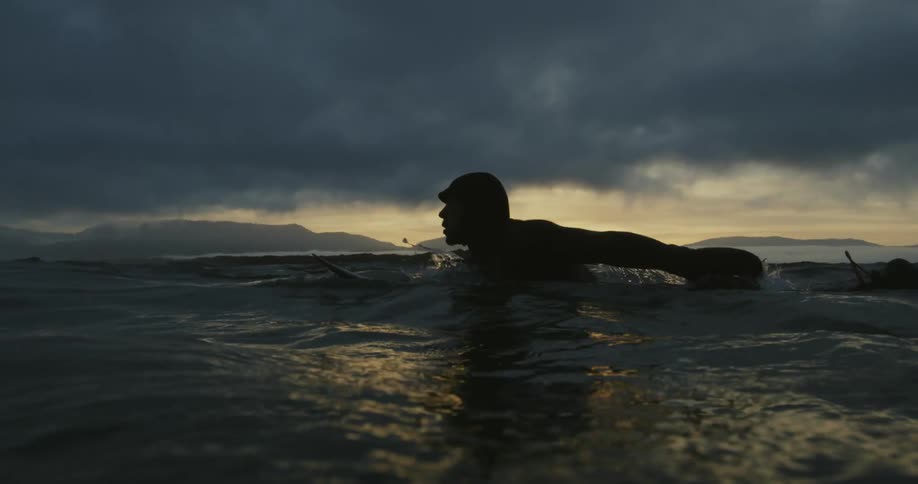 A man paddles on his surfboard in the ocean