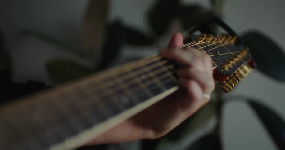 A close up of a persons hand on a guitar and playing the cords