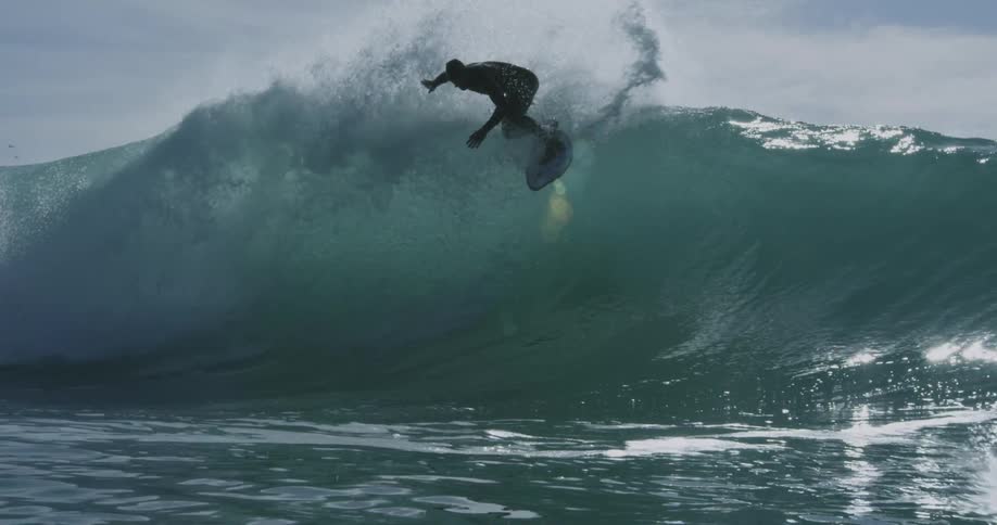 Man in wetsuit surfs waves off the coast