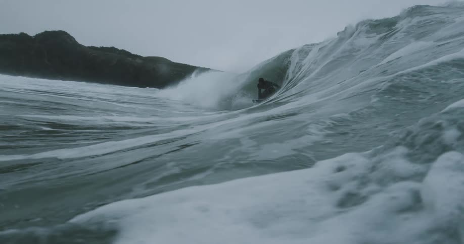 Man in wetsuit surfs wave off the coast