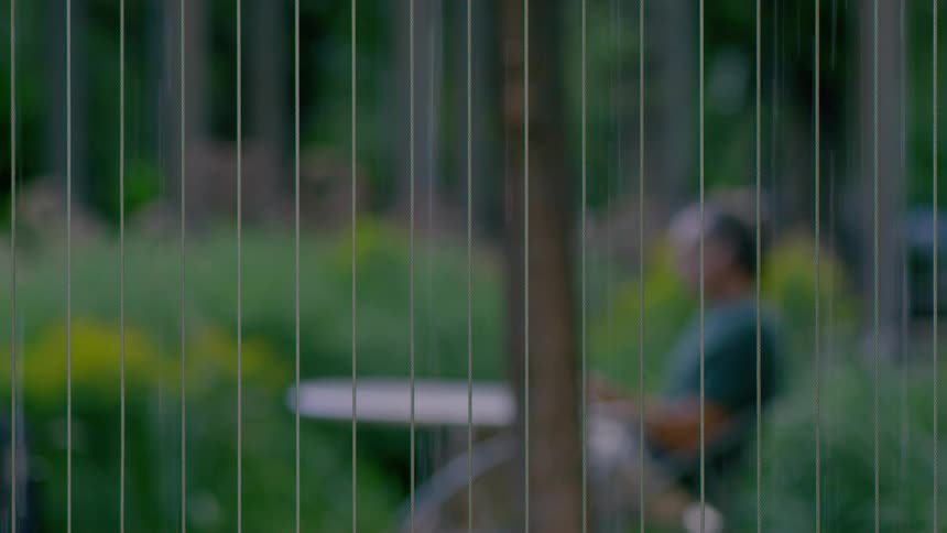 A reflection of a person sitting at a table as water drips down in lines