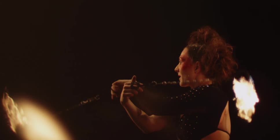 A woman is doing a fire dance with two ropes that have the ends on fire