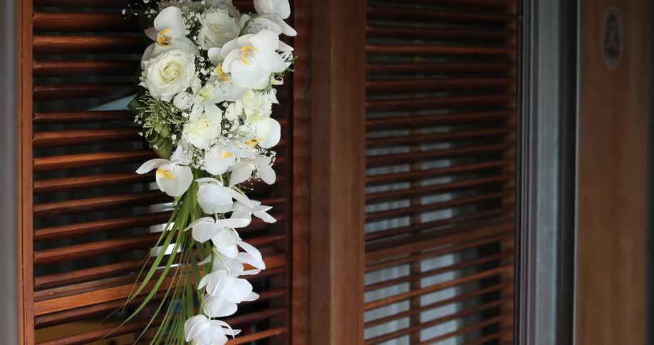 A garland made of tropical flowers hangs off a slatted door