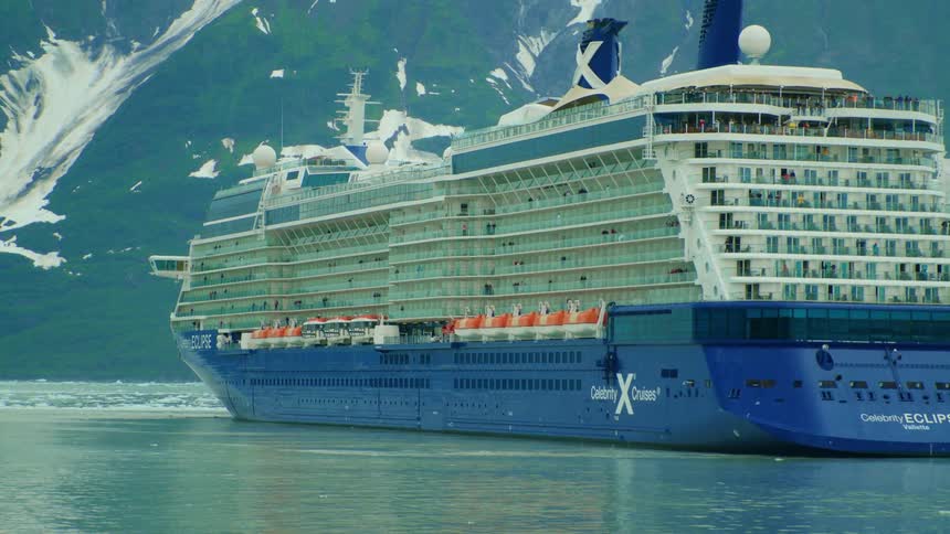 Solstice class cruise ship sailing on water with high mountain in the background