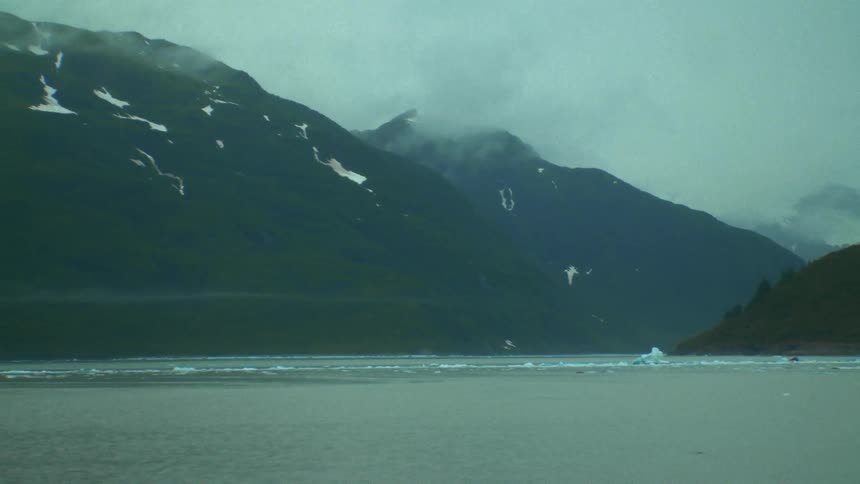 Ocean near mountains during winter season is displayed
